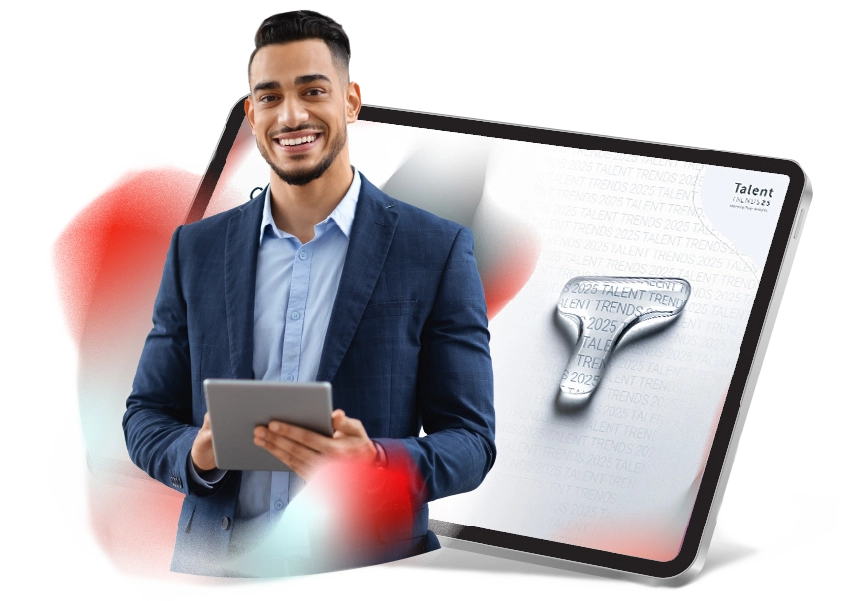 Ein lächelnder Mann hält ein Tablet in den Händen und steht vor einem Bild eines Tablets, auf dem die erste Seite von Talent Trends angezeigt wird.