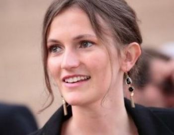 Person mit Ohrringen und lächelndem Gesicht.