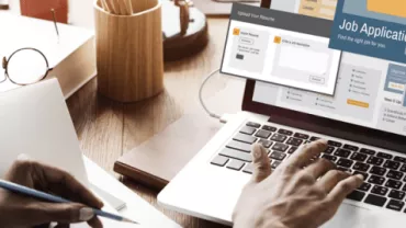 Person arbeitet an einem Laptop mit einer Jobbewerbung auf dem Bildschirm.