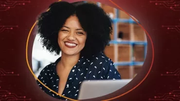 Lächelnde Person mit lockigem Haar, im Hintergrund unscharfes Bücherregal.