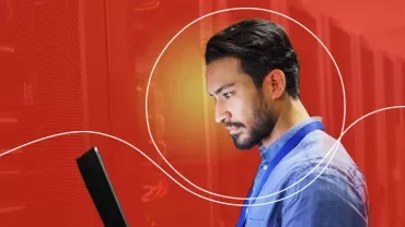 Person arbeitet an einem Laptop in einem Serverraum.