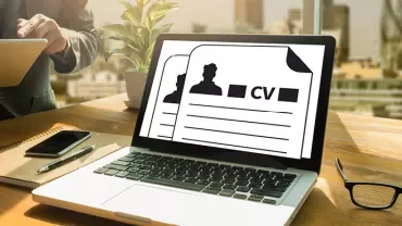 Laptop auf einem Schreibtisch mit einem Lebenslauf auf dem Bildschirm.