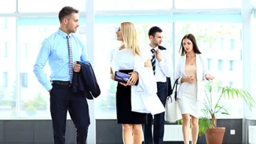 Gruppe von Menschen in Businesskleidung geht durch ein modernes Bürogebäude.
