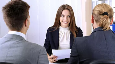 Drei Personen in einem Meeting, eine Person hält Dokumente.