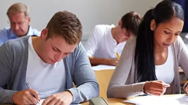 Personen schreiben konzentriert in einem Klassenzimmer.