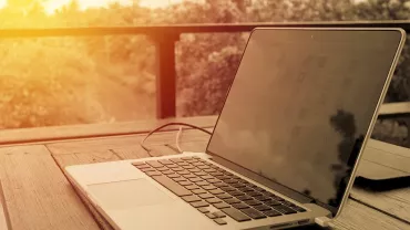 Laptop auf Holztisch in der Sonne