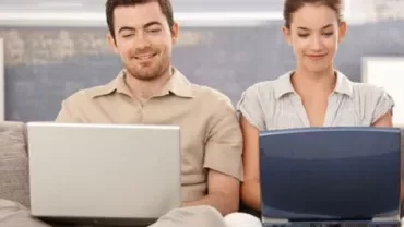 Zwei Personen arbeiten gemeinsam an Laptops.