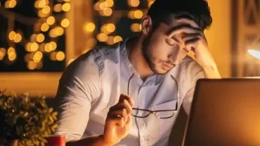 Person arbeitet konzentriert am Laptop bei Nachtlicht.