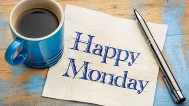 Blaue Tasse Kaffee neben Serviette mit 'Happy Monday'.
