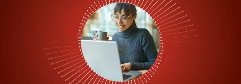 Person arbeitet am Laptop und hält eine Tasse.