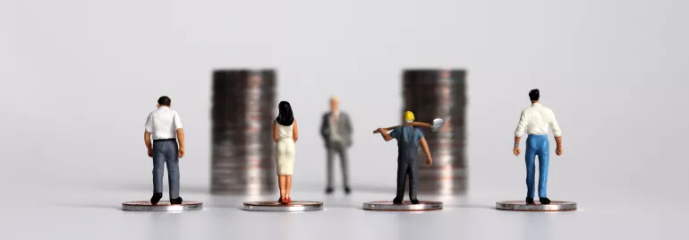 Miniaturfiguren auf Münzen vor Stapeln, die unterschiedliche Berufe darstellen
