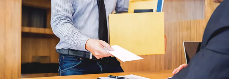Person mit einem Ordner in der Hand übergibt einen Brief an eine sitzende Person.