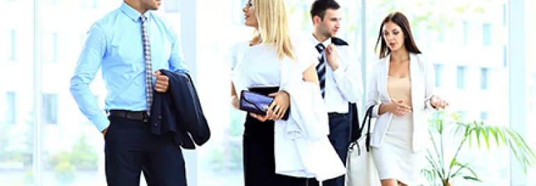 Gruppe von Menschen in Businesskleidung geht durch ein modernes Bürogebäude.