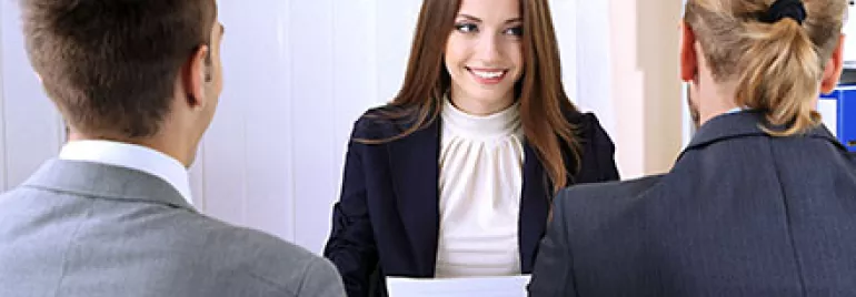 Drei Personen in einem Meeting, eine Person hält Dokumente.