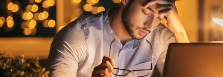 Person arbeitet konzentriert am Laptop bei Nachtlicht.