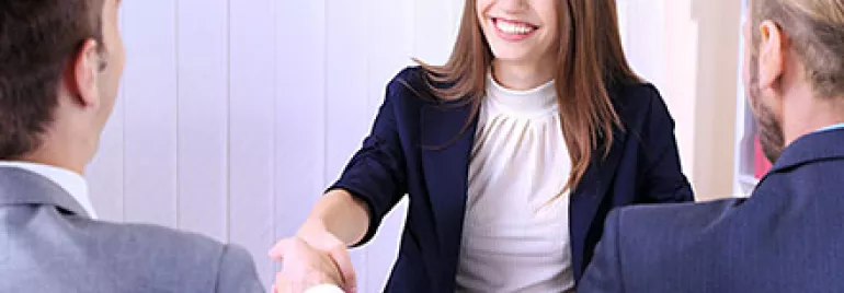 Person am Tisch schüttelt Hände in professioneller Umgebung.