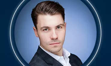 Porträt einer Person in Anzug vor blauem Hintergrund.