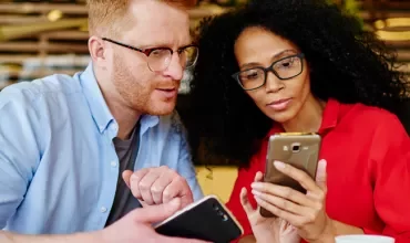 Zwei Personen schauen auf ihre Smartphones.