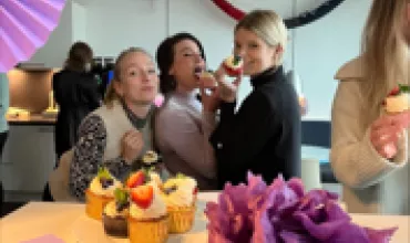 Personen genießen Cupcakes bei einer Feier, Dekoration im Hintergrund.