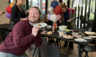 Person beim Feiern mit Ballons und Snacks im Hintergrund.