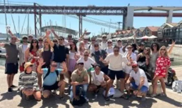 Gruppe von Menschen posiert fröhlich vor einer Brücke und Booten