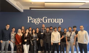 Gruppe von Menschen steht vor einer blauen Wand mit 'PageGroup'-Logo.