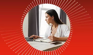 Eine Frau, konzentriert auf ihren Laptop, sitzt in einem Büroarbeitsplatz.